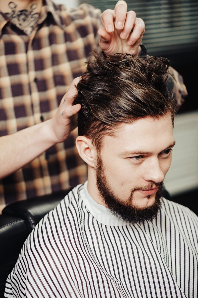 Barber makes hairstyling to a client